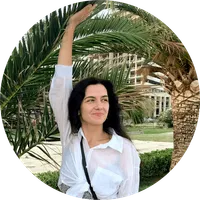 Victoria Seniuk smiling under palm trees, wearing a white shirt
