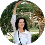 Victoria Seniuk smiling under palm trees, wearing a white shirt